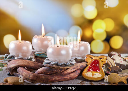 Corona di Avvento con candele accese sul tavolo Foto Stock