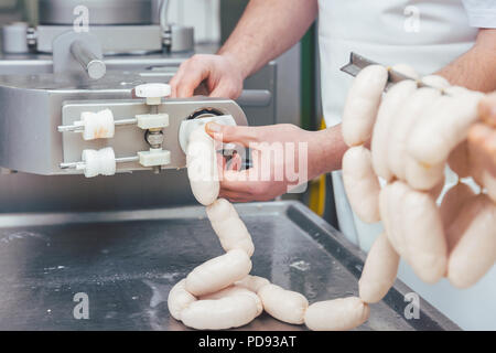 Macellaio in macelleria salsicce di riempimento Foto Stock