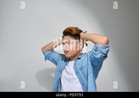 Orinato uomo collegando le orecchie con le dita non vuole ascoltare isolato sul muro grigio sfondo Foto Stock