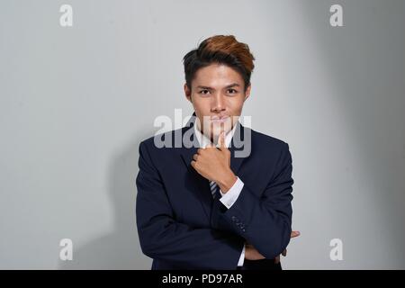 Bel giovane con gli occhiali, sorridente e toccando il suo mento Foto Stock