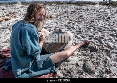 Un uomo rendere Viking iscrizioni in pietra sulla spiaggia durante Moesgaard Viking discutibile, Aarhus, Danimarca Foto Stock