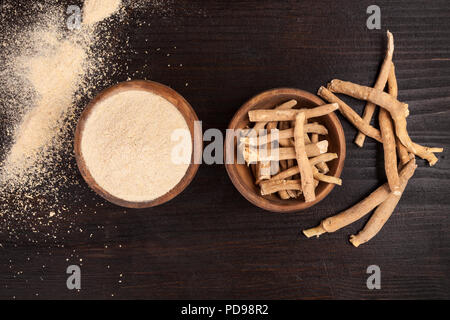 Radici e polvere di Ashwagandha noto anche come ginseng indiano su sfondo di legno, vista dall'alto. Foto Stock