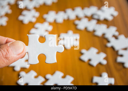 Closeup mano di uomo con parti puzzle con, soluzioni aziendali, il successo e il concetto di strategia Foto Stock
