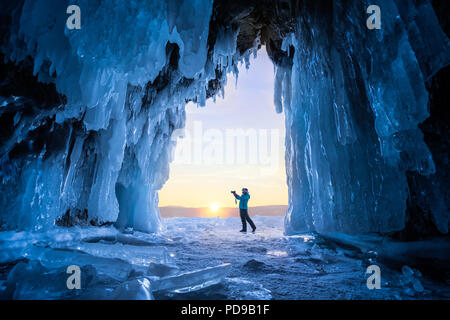 Turistico sconosciuto nella parte anteriore della caverna di ghiaccio sulla isola di Olkhon al lago Baikal in Siberia durante l'inverno. Foto Stock