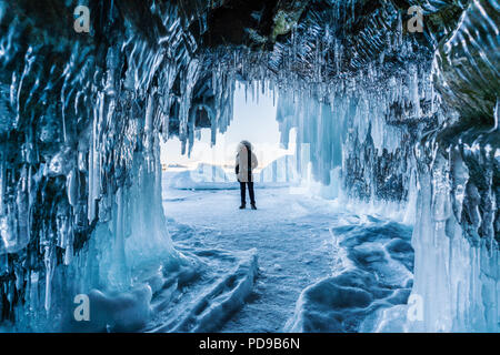 Viaggiare in inverno, un uomo in piedi sul lago ghiacciato Baikal con la grotta di ghiaccio di Irkutsk in Siberia, Russia Foto Stock