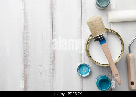 Vernice, spazzola e altre forniture di pittura su bianco tavolo in legno Foto Stock
