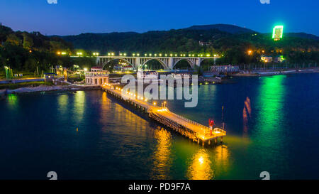 Drone vista del molo di Matsesta stazione marino sullo sfondo dell'illuminato Matsesta viadotto e montagne al crepuscolo, Sochi, Russia Foto Stock