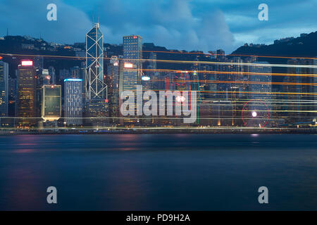 Sentieri di luce da un passaggio di traversata in battello sul Victoria Harbour Hong Kong al tramonto. Foto Stock