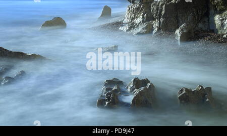 Sfocata onde del mare su una spiaggia rocciosa in East Devon su Jurassic Coast Foto Stock