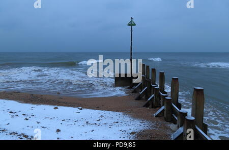 Groyne in legno vicino alla città di Seaton nel Devon . Le onde del mare la fusione della neve sulla spiaggia di ciottoli su Jurassic Coast. Foto Stock