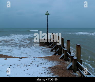 Groyne in legno vicino alla città di Seaton nel Devon . Le onde del mare la fusione della neve sulla spiaggia di ciottoli su Jurassic Coast. Foto Stock