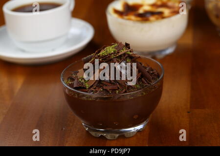 Gustosi profiteroles con crema e glassa di cioccolato su una piastra Foto Stock