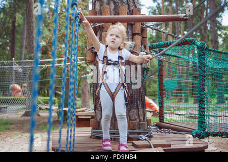 Brave bambina passa un ostacolo nella fune park. Foto Stock