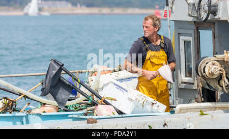 Il Solent, Hampshire, Regno Unito; 7 agosto 2018; Closeup del pescatore sbudellare un pesce mentre a bordo di una piccola barca da pesca in mare Foto Stock