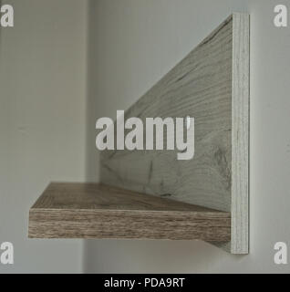 Vuoto grigio scaffale di legno sulla parete bianca, vista laterale Foto Stock