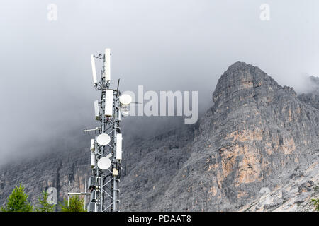 La stazione trasmittente sulla cima di una montagna con nuvole temporalesche raccolta attorno al picco di una montagna. Concetto di interferenza a causa di cattive condizioni del tempo Foto Stock