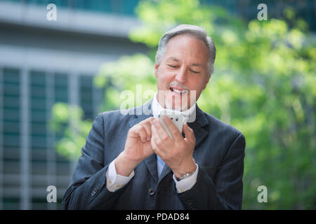 Ritratto di un sorridente imprenditore senior utilizzando il suo telefono cellulare Foto Stock