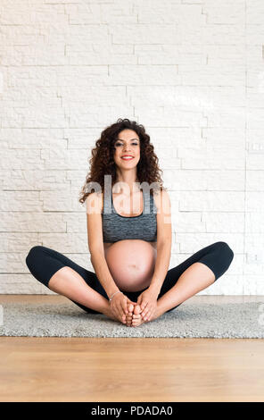 Donna incinta facendo esercizi di fitness Foto Stock