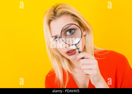 Donna bionda in abito con lente di ingrandimento Foto Stock