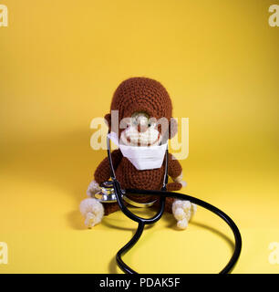 Medical Monkey giocattolo imbottito panoramico. Simpatico peluche scimmia marrone che indossa una maschera di ospedale e medici stetoscopio. Foto Stock