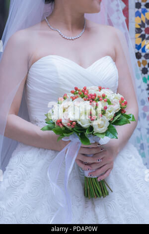 Vista ravvicinata della splendida colorato bouquet di nozze nella mano di una sposa e il simbolo dell'amore Foto Stock