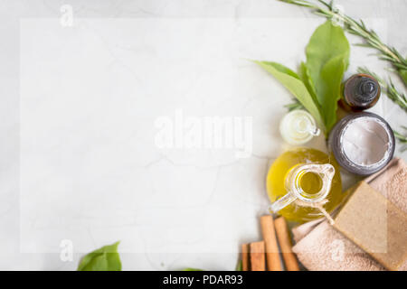 Organici prodotti skincare flatlay con copia spazio, faccia bottiglia di olio, olio di oliva e maschera di argilla, sapone naturale su asciugamano, vista dall'alto su sfondo di calcestruzzo Foto Stock