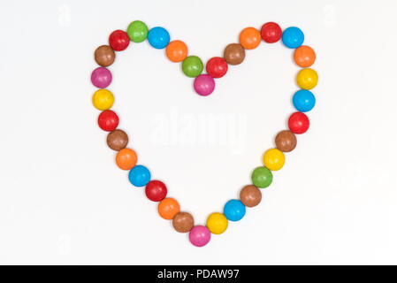 Colorato forma di cuore fatta di rivestite di zucchero candito al cioccolato dolci ans isolati su sfondo bianco Foto Stock