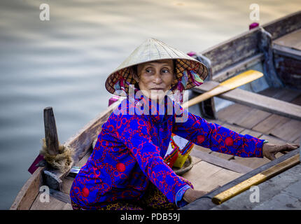 Asian Lady ottenere pronto a prendere i turisti fuori sulla sua barca sul fiume di Hoi An. Shes che indossa un molto colorato e top hat. rilascio di foto Foto Stock