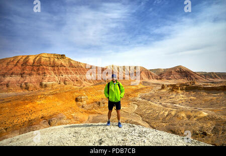 Turisti in giacca verde con surreale di rosso e di giallo in montagna in background nel parco deserto Altyn Emel in Kazakistan Foto Stock