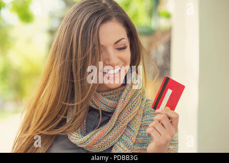 Allegro eccitato giovane donna con carta di credito in piedi all'aperto in una giornata di sole Foto Stock