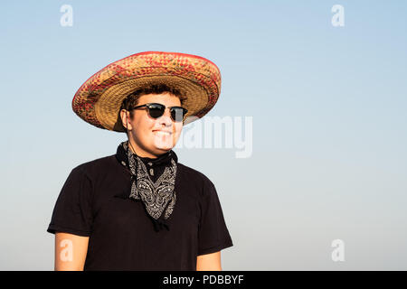 Allegro giovane maschio persona in sombrero nel cielo chiaro dello sfondo. Indipendenza del Messico festosa concetto di uomo che indossa national Mexican Hat e western st Foto Stock