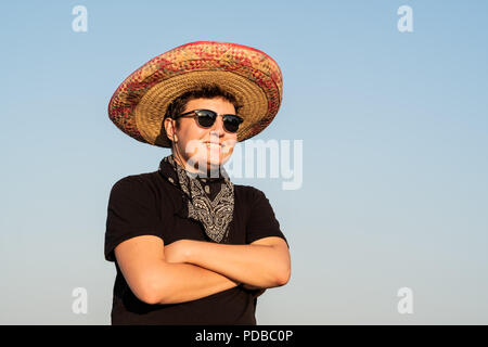 Allegro giovane maschio persona in sombrero nel cielo chiaro dello sfondo. Indipendenza del Messico festosa concetto di uomo che indossa national Mexican Hat e western st Foto Stock