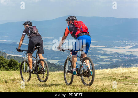 Motociclisti ciclismo su un sentiero di montagna uomini in bicicletta collina Velka Javorina confine ceco-slovacco nei Carpazi bianchi in bicicletta campagna su una collina Foto Stock