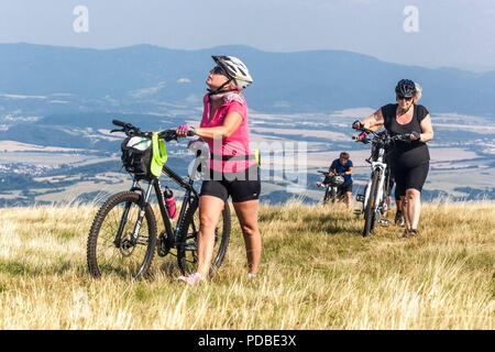 Ciclisti in bicicletta su un sentiero di montagna, la collina Velka Javorina, confine ceco-slovacco in White Carpathians Women che spingono una salita Foto Stock