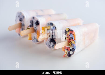 Vista ravvicinata di freschi congelati popsicles fatti in casa con frutti e bacche su grigio Foto Stock