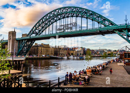 Persone bere fuori dal fiume Brew Co contenitore bar in una serata estiva dal Tyne Bridge guardando verso Newcastle, Gateshead, Regno Unito. Foto Stock