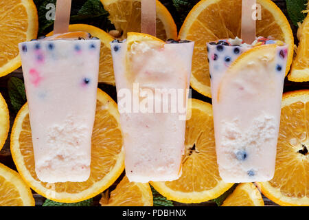 Vista superiore del gourmet popsicles fatti in casa con frutti e bacche su fettine di arancia Foto Stock