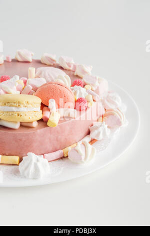 Rosa torta con crema di burro, marshmallows e macarons sulla piastra bianca Foto Stock