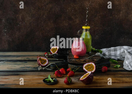 Fresco e salutare i frullati sul tavolo rustico con bacche e frutti della passione Foto Stock