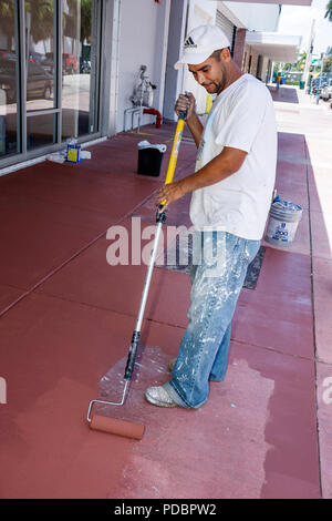 Miami Beach Florida,uomo ispanico uomini maschio,pittore,lavoratore,strada,marciapiede,calcestruzzo,rullo,lavoro,lavoro,dipendenti lavoratori dipendenti personale,occupazione,blu c Foto Stock