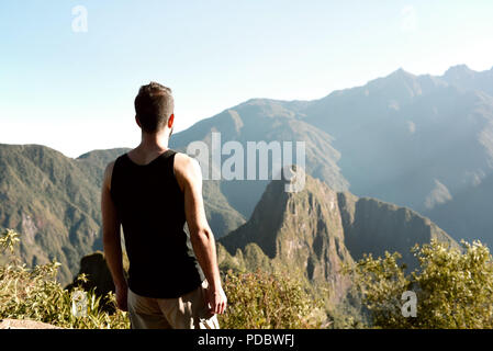 Da ragazzo dietro, in piedi sul Machu Picchu Mountain guardando Huayna Picchu mountain e antica città di Machu Picchu. Lug 2018 Foto Stock