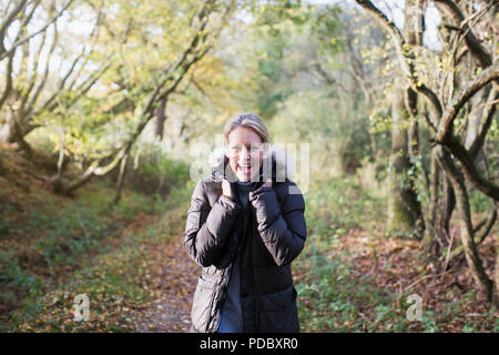 Ritratto entusiastico donna matura che indossa parka in autunno boschi Foto Stock