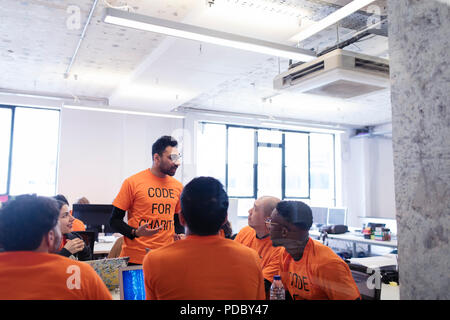 Hacker che conduce la discussione, codifica per la carità a hackathon Foto Stock