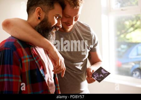 Affettuoso gay maschio giovane guardando foto di ultrasuoni Foto Stock