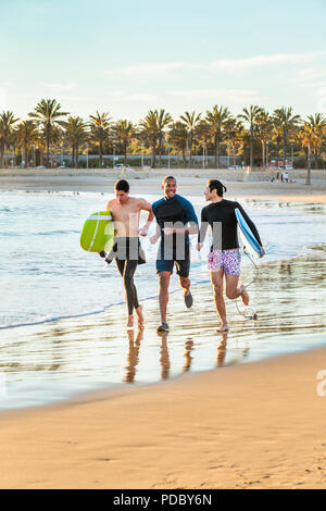 Maschio entusiasta surfers in esecuzione con tavole da surf su Ocean Beach Foto Stock