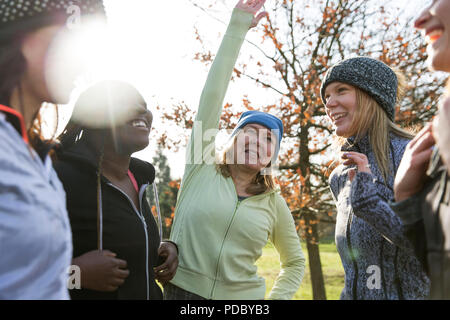 Femminile di stretching e parlando nel soleggiato parco Foto Stock