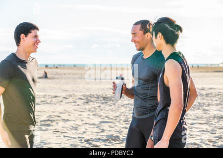 Maschio amici runner in appoggio, parlando di sunny beach Foto Stock