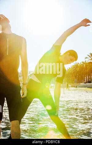 Surfista maschio stretching di sunny beach Foto Stock