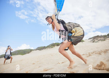 Femmina in esecuzione di parapendio, tenendo fuori sulla spiaggia Foto Stock