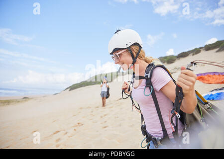 Donna sorridente con parapendio attrezzatura sulla spiaggia Foto Stock
